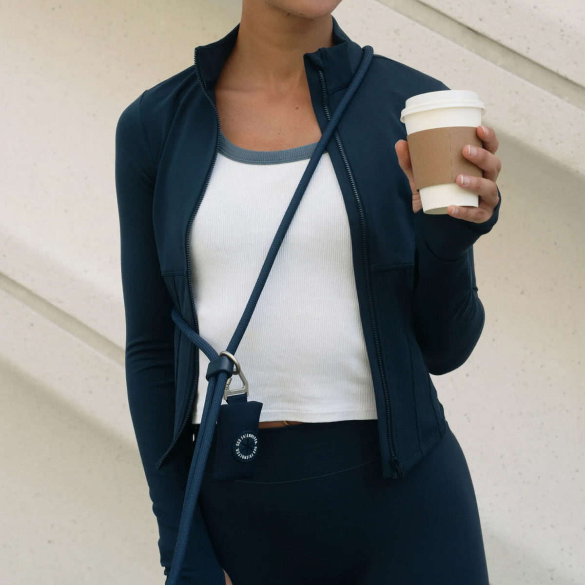 Navy Blue poop bag holder attached to a hands-free dog leash worn around the shoulder